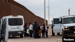 FILE - Migrants seeking asylum in the U.S. are processed by the U.S. border patrol after crossing the border from Mexico at Yuma, Arizona, Jan. 22, 2022. 