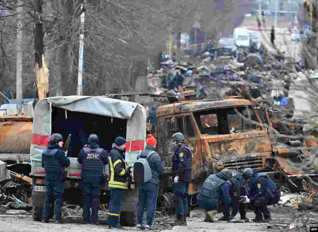 Los ingenieros de campo del Servicio Estatal de Emergencia de Ucrania realizan la limpieza de minas entre los vehículos destruidos en una calle de Bucha el 5 de abril de 2022, mientras las autoridades ucranianas dicen que se han recuperado más de 400 cuerpos civiles de la región más amplia de Kiev, muchos de los cuales fueron enterrados en tumbas.