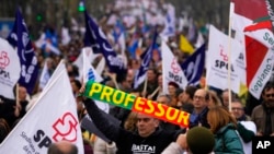 A protester holds a scarf with the word 'teacher' as tens of thousands march down Lisbon's Liberdade Avenue during a demonstration by teachers in Lisbon, Feb. 11, 2023. 