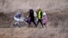 Una mujer con su bebé camina con otras personas que huyen de Ucrania, en el cruce fronterizo de Medyka, Polonia.