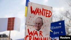 Una persona sostiene un cartel con una imagen del presidente ruso Vladimir Putin durante una protesta en el Reino Unido.