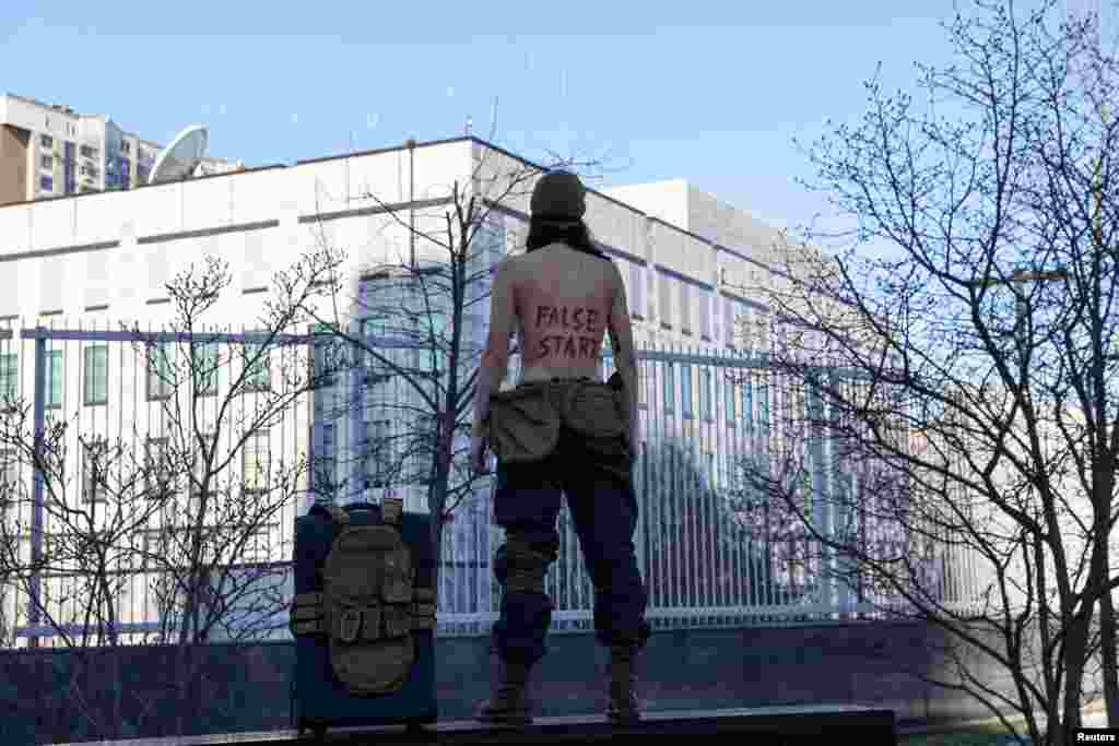 An activist of women&#39;s rights group Femen stages a protest outside the U.S. Embassy demanding American diplomats not to leave the city in Kyiv, Ukraine.