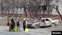 Los refugiados se reúnen en una calle cuando salen de la ciudad durante el conflicto entre Ucrania y Rusia en el asediado puerto sur de Mariupol, Ucrania, el 20 de marzo de 2022. REUTERS/Alexander Ermochenko