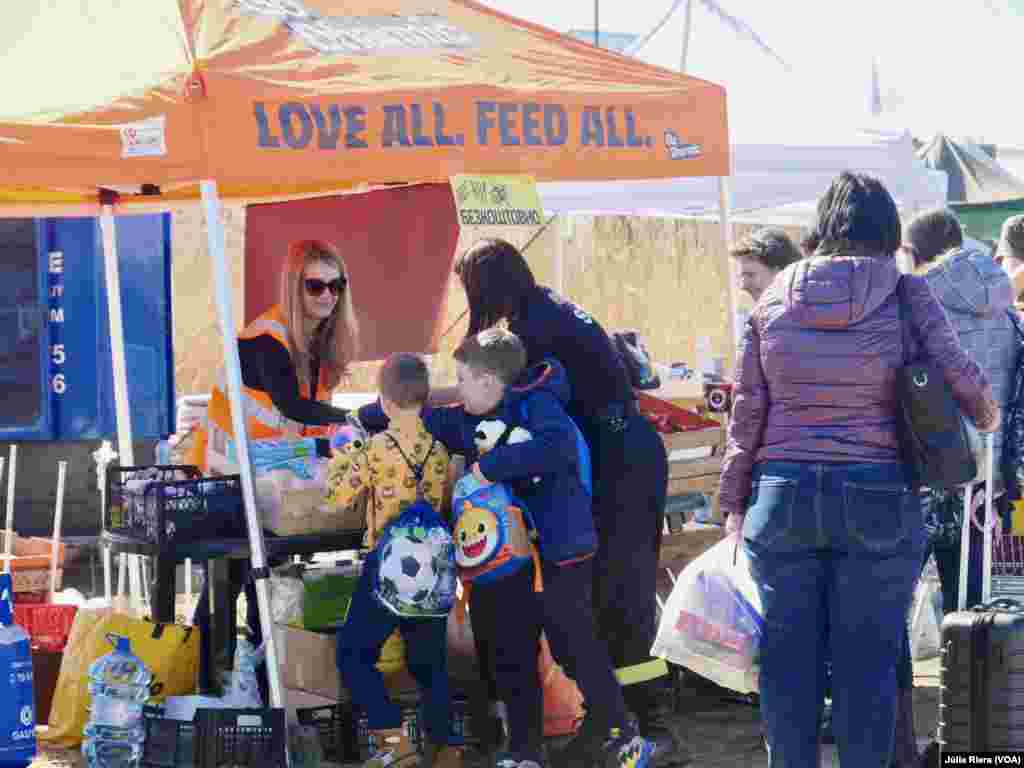 Voluntaria de organización internacional reparte fruta a unos refugiados.