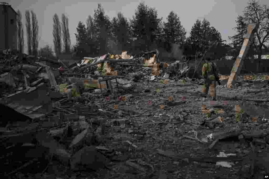 Un voluntario de las Fuerzas de Defensa Territorial de Ucrania camina sobre los escombros de un lavadero de autos destruido por un bombardeo ruso en Baryshivka, al este de Kiev, Ucrania, el viernes 11 de marzo de 2022. (Foto AP/Felipe Dana)
