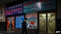 FILE - A man walks past a store advertising cargo shipping to Russia and other countries, along a street in Beijing, March 4, 2022. 