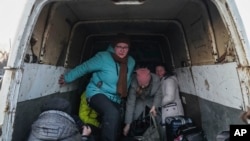 Desplazados internos de Mariúpol salen de una camioneta cuando llegan a un centro de refugiados en Zaporizhia, Ucrania, el 25 de marzo de 2022.