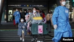 身穿防护服的韩国军人引领一组从中国飞抵仁川国际机场的旅客。（2023年1月12日）