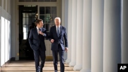 President Joe Biden and French President Emmanuel Macron walk down the Colonnade to the Oval Office at the White House, Dec. 1, 2022.