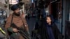 Seorang perempuan tampak menatap anggota pasukan Taliban ketika berjalan di salah satu area di Kabul, pada 26 Desember 2022. (Foto: AP/Ebrahim Noroozi)