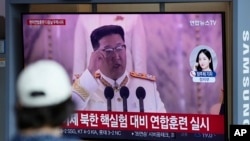 A woman watches a TV screen showing a news program reporting about North Korea's missile launch with a file footage of North Korean leader Kim Jong Un, at a train station in Seoul, South Korea, Sunday, June 5, 2022.