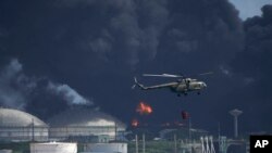 Un helicóptero arroja agua sobre la base de supertanqueros de Matanzas, mientras los bomberos intentan sofocar un incendio que comenzó durante una tormenta eléctrica la noche anterior, en Matazanas, Cuba, el sábado 6 de agosto de 2022. Las autoridades cubanas dicen que un rayo cayó sobre un tanque de almacenamiento de petróleo crudo en la base, provocando un incendio que provocó cuatro explosiones que hirieron a más de 70 personas. (Foto AP/Ramón Espinosa)