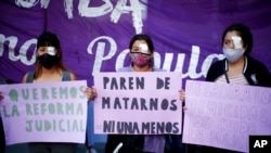 Mujeres con un ojo tapado sostienen carteles que exigen una reforma judicial, durante una protesta contra la violencia de género, en Buenos Aires, el 17 de febrero de 2021.
