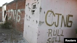 Una fachada acribillada a balazos contiene las siglas del Cártel Jalisco Nueva Generación (CJNG) en El Aguaje, municipio de Aguililla, zona donde opera esta organización criminal, en el estado de Michoacán, México, el 23 de abril de 2021.