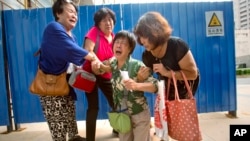 FILE - Bao Lanfang, second from right, whose daughter-in-law, son and granddaughter were aboard Malaysia Airlines Flight 370, kneels in grief while speaking to journalists outside the company's offices in Beijing, Aug. 6, 2015. 