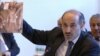 This image taken from UNTV via APTN shows Amhad al-Jarba, the head of Syria's Western-backed Syrian National Coalition, holding up an image of alleged torture victims, during the Syrian peace talks in Montreux, Switzerland, Jan. 22, 2014. 