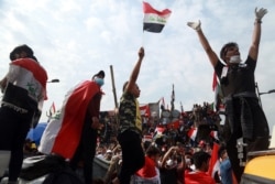 FILE - Anti-government protesters stand on barriers set up by Iraqi security forces to close the Joumhouriya Bridge leading to the Green Zone government area, in Baghdad, Nov. 3, 2019.