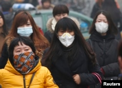 Commuters wearing masks make their way amid thick haze in the morning in Beijing February 26, 2014. China's north is suffering a pollution crisis, with the capital Beijing itself shrouded in acrid smog.
