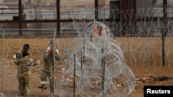 ARCHIVO - Miembros de la Guardia Nacional de Texas colocan alambradas de púas cerca de la frontera entre EEUU y México al otro lado de Ciudad Juárez, México, el 23 de enero de 2024.