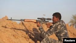 A Shiite fighter takes aim while patrolling in Jurf al-Sakhar, Iraq, which Iraqi security forces retook from Islamic State militants, Oct. 25, 2014. 