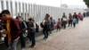 FILE - People line up to cross into the United States to begin the process of applying for asylum near the San Ysidro port of entry in Tijuana, Mexico, July 26, 2018. 