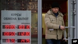 FILE - A man leaves a bank next to an exchange sign showing the currency exchange rates in Moscow, Dec. 20, 2024.