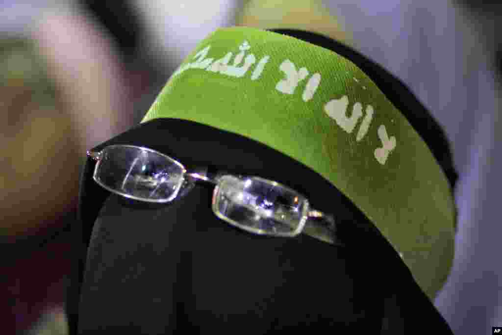 Seorang pendukung Mohamed Morsi memakai burqa dan ikat kepala bertuliskan "Tidak ada Tuhan selain Allah, dan Muhammad Rasul Allah," dalam sebuah demonstrasi di depan Cairo University (167). (AP/Amr Nabil)