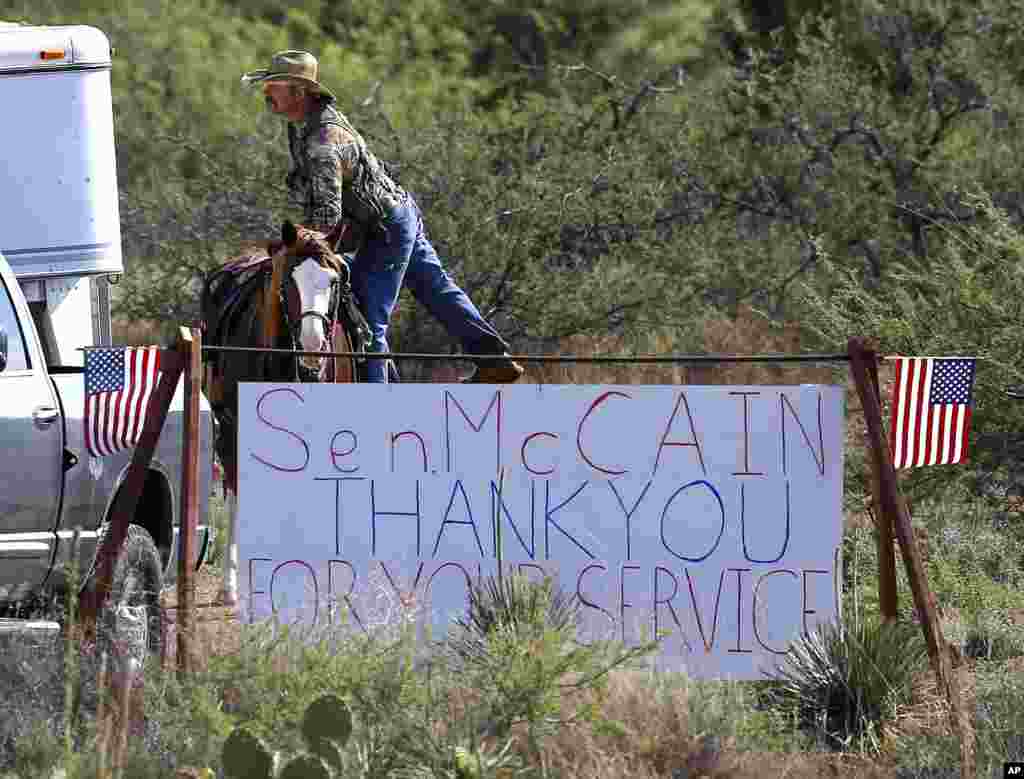 A rancher gets off his horse at the entrance to the McCain ranch complex, Aug. 25, 2018, in Cornville, Ariz.