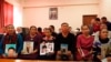 在哈萨克斯坦阿拉木图一个中国哈萨克族人组织的办公室里，人们手举在新疆失踪亲属的照片。（2018年12月7日）