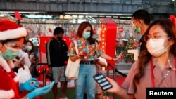 People check their temperature as they visit the Christmas light festival in Bangkok, Thailand, Dec. 21, 2020. 