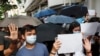 Supporters raise white paper to avoid slogans banned under the national security law as they support arrested anti-law protester outside Eastern court in Hong Kong