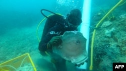 En la foto del ISEAS - Yusof Ishak Institute, publicada el 16 de junio de 2021, se muestra a un buzo sosteniendo artículos de cerámica china Iongquan que fueron descubiertos en un naufragio en las aguas de Pedra Branca, Singapur. 