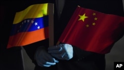 El canciller venezolano Jorge Arreaza sostiene las banderas de Venezuela y China al recibir especialistas y suministros médicos de China en el Aeropuerto Internacional Simón Bolívar de Caracas el 30 de marzo de 2020.