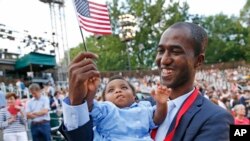 Alpha Saliou Diallo, a refugee from Guinea, holds his daughter, Aisha, after he became a U.S. citizen during a special naturalization ceremony commemorating World Refugee Day at the Delacorte Theater in New York City's Central Park, June 20, 2016.