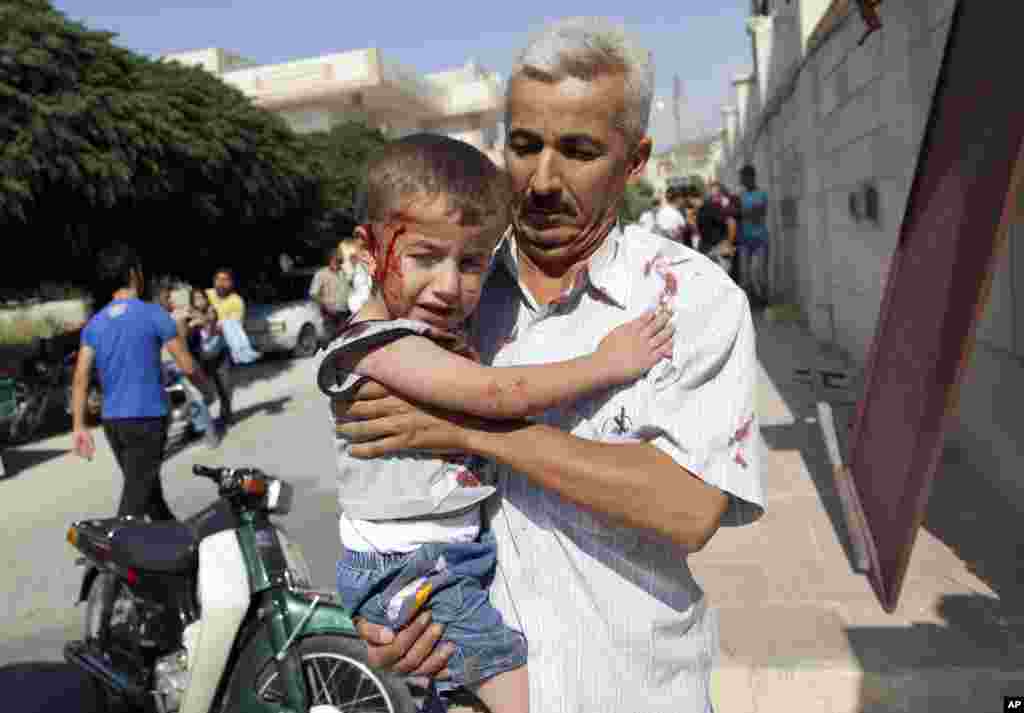 A Syrian man carries an injured child to a field hospital after an air strike hit homes in Azaz on the outskirts of Aleppo, August 15, 2012.