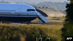 Deux policiers en patrouillent près du Boeing 767 qui devait transporter des demandeurs d'asile vers le Rwanda à la base militaire d'Amesbury, au Royaume-Uni, le 14 juin 2022.