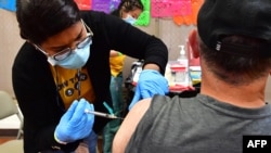 Seorang perawat tampak memberikan suntikan penguat atau booster vaksin COVID-19 kepada warga di sebuah klinik di Los Angeles, pada 5 Mei 2022. (Foto: AFP/Frederic J. Brown)