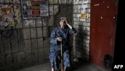 Una anciana se sienta en la entrada de un edificio de apartamentos en la ciudad de Lysychansk, en la región oriental de Ucrania de Donbas, el 14 de junio de 2022, en medio de la invasión rusa de Ucrania.