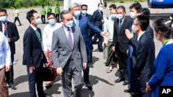 In this photo provided by Myanmar's Ministry of Information, Chinese Foreign Minister Wang Yi, center, is welcomed by Myanmar Foreign Ministry representatives and Chinese embassy officials upon his arrival at Nyaung Oo Airport in Bagan, Myanmar, July 2, 2022.