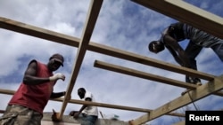 FILE - Workers repair the roof of a holiday resort days after Cyclone Pam in Port Vila, capital city of the Pacific island nation of Vanuatu.