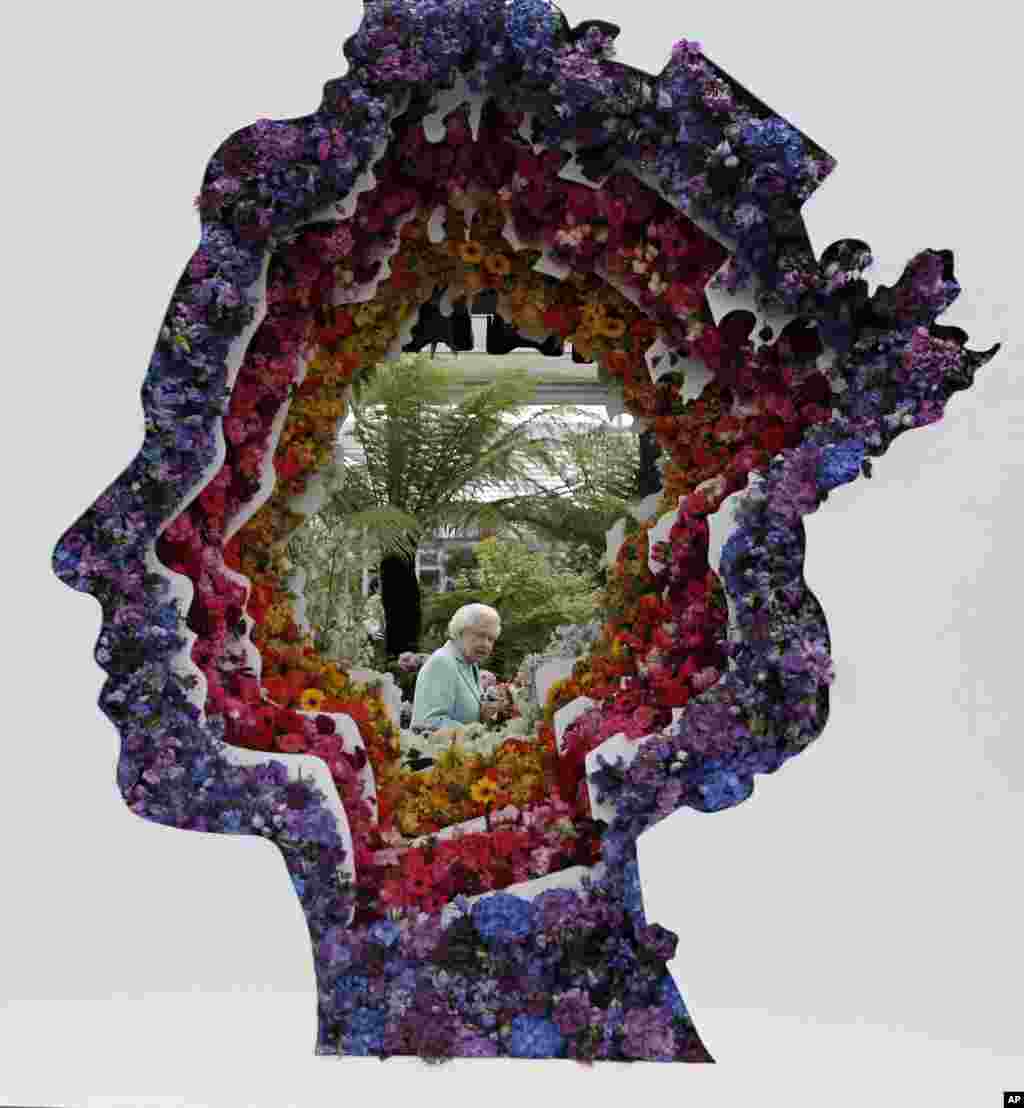 Britain's Queen Elizabeth is pictured through a gap in a floral exhibit by the New Covent Garden Flower Market at the 2016 Chelsea Flower Show in central London.