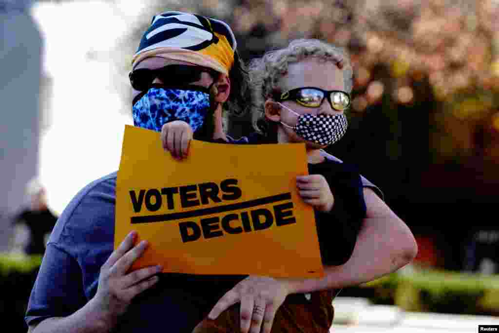 A Biden supporter holds a sign reading "voters decide" at a 'Stop the Steal' protest held by supporters of U.S. President Donald Trump in Madison, Wisconsin, Nov. 7, 2020.