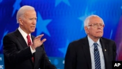 FILE - From left, Democratic presidential candidates, Sen. Bernie Sanders, I-Vt., former Vice President Joe Biden, talk before a Democratic presidential primary debate, Feb. 25, 2020.