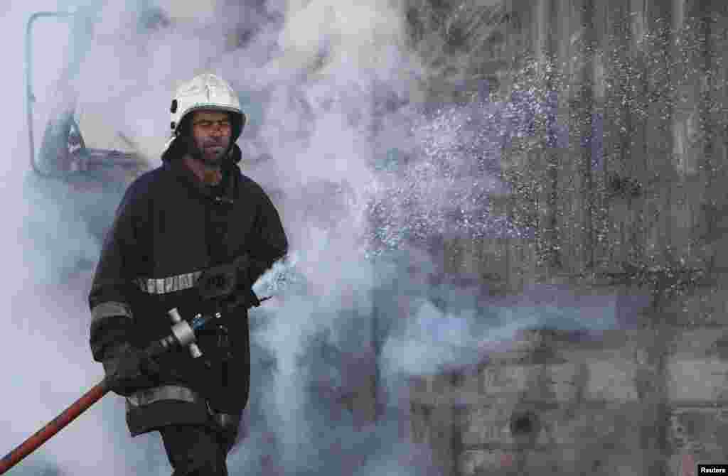 A civil defense worker puts out a fire after what activists said were explosive barrels thrown by forces loyal to President Bashar al-Assad, al-Inzarat district, Aleppo, Feb. 18, 2014. 