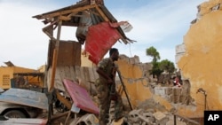 Tentara Somalia berdiri dekat gedung yang hancur di dekat kantor polisi di Mogadishu, Somalia (9/5). (AP/Farah Abdi Warsameh)