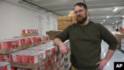 Anthony Reinert, director of programs for the Food Bank of Alaska, poses stands near pallets of canned food at the warehouse in Anchorage, Alaska, on April 4, 2023.