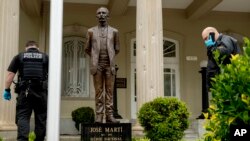 Lubang-lubang bekas peluru tampak di tiang di belakang patung pahlawan kemerdekaan Kuba, José Martí, sementara penyelidik keamanan federal AS menyelidiki serangan dari seorang pria bersenjata di Kedutaan Besar Kuba di Washington D.C, 30 April 2020.