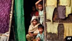 FILE - A Myanmar Muslim family, who identify themselves as long-persecuted Rohingya Muslims, look out from their tents at Da Paing camp for Muslim refugees in north of Sittwe, Rakhine State, western Myanmar, April 2, 2014. 