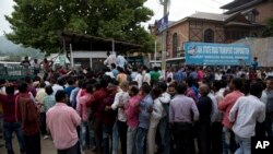 Indian migrant workers wait outside the government transport yard waiting to buy bus tickets to leave the region, during curfew in Srinagar, Indian controlled Kashmir, Aug. 7, 2019.