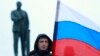A man holds the Russian flag in front of a statue of Lenin in Simferopol, Crimea, on March 1, 2014.